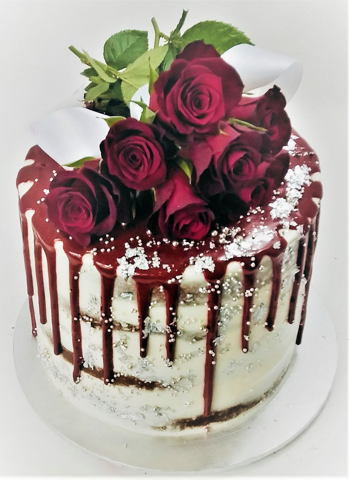 Naked cake with red icing drip and red roses